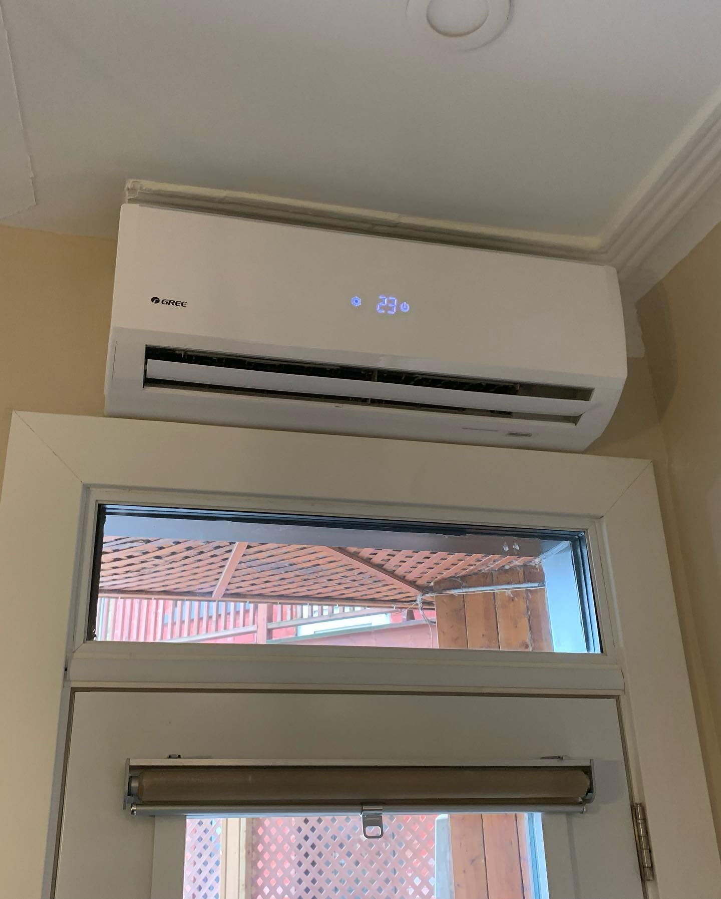 A white air conditioner is hanging from the ceiling above a door.