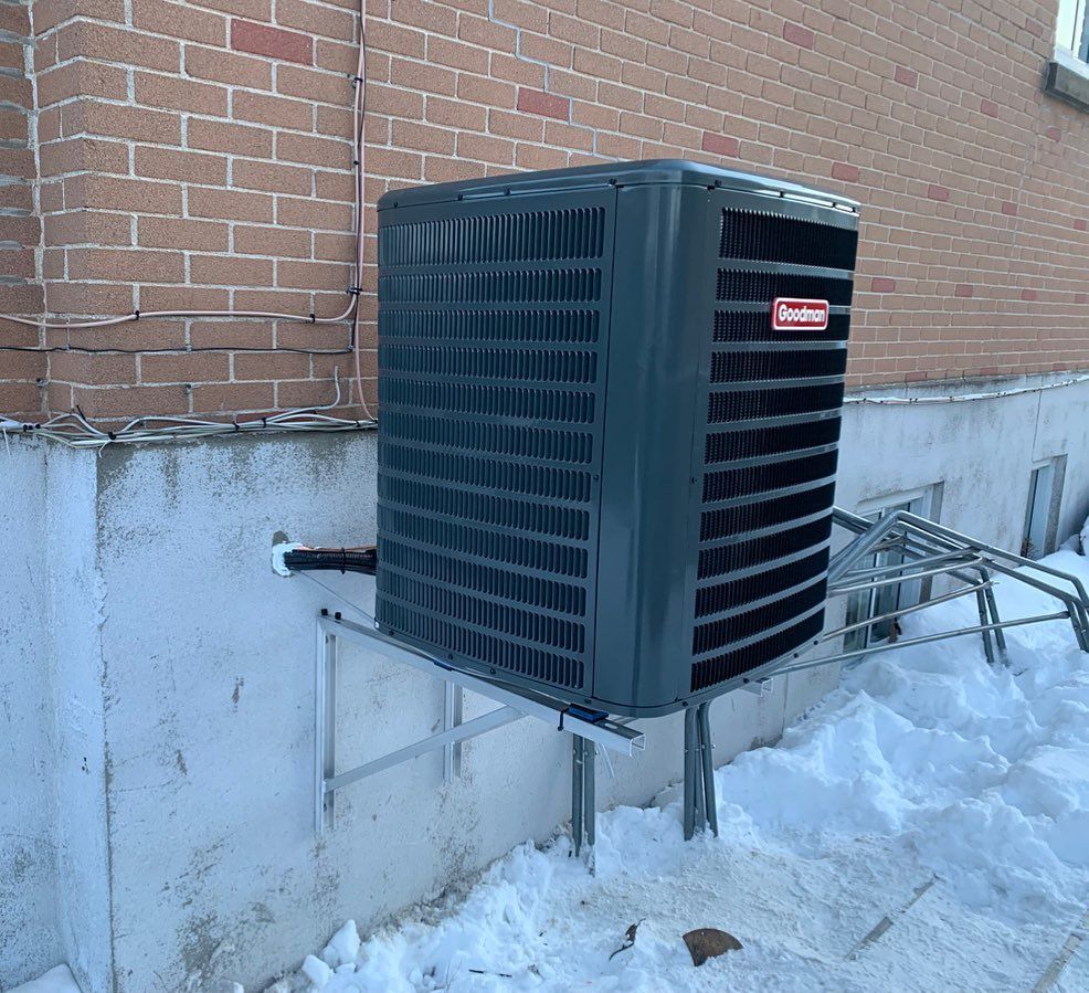 An air conditioner is mounted on the side of a brick building