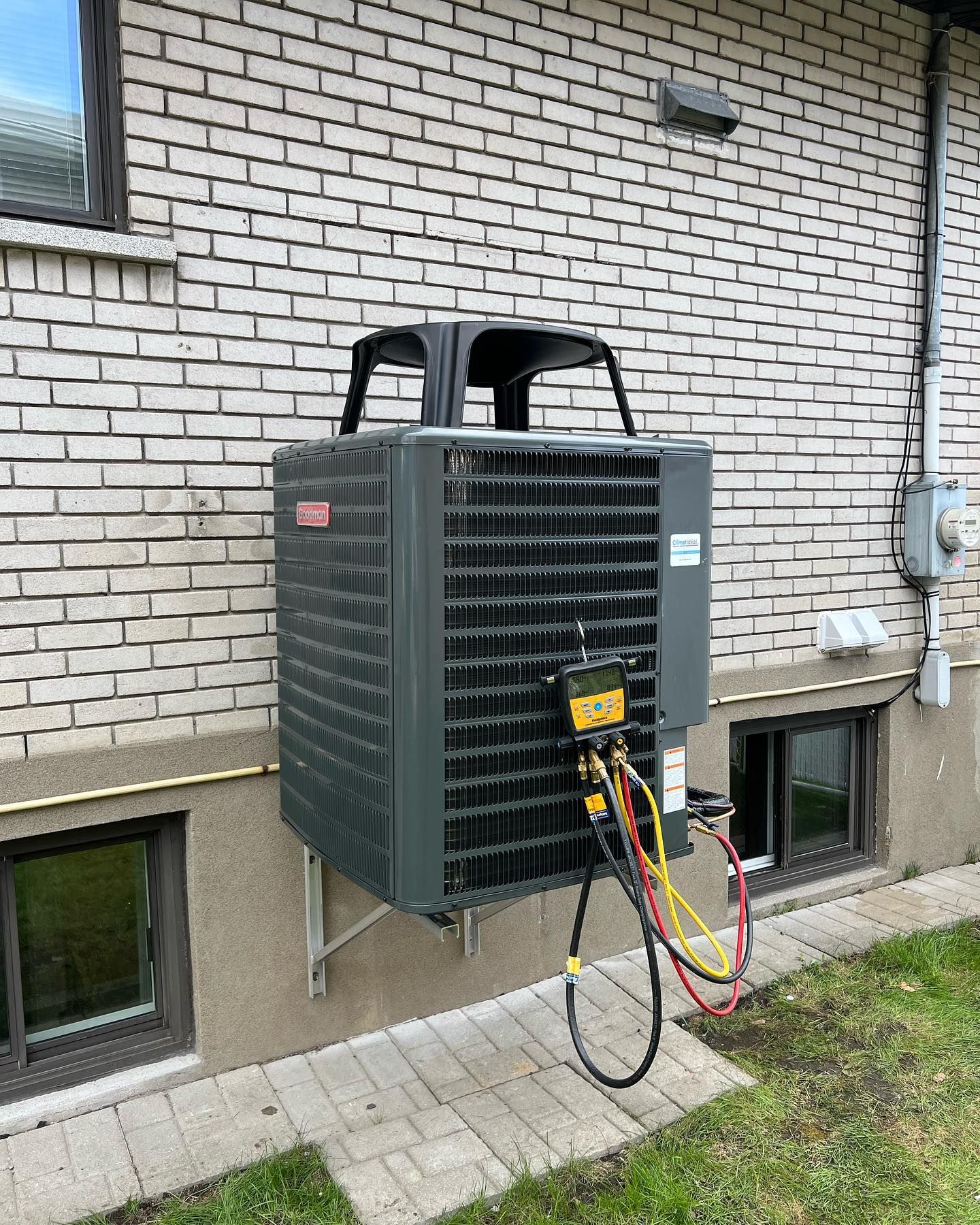 A large air conditioner is mounted on the side of a brick building.