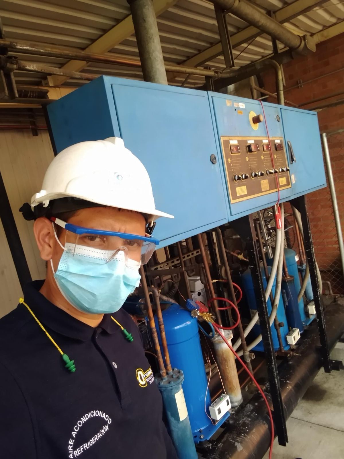 Un hombre que lleva un casco y una máscara está parado frente a una máquina.