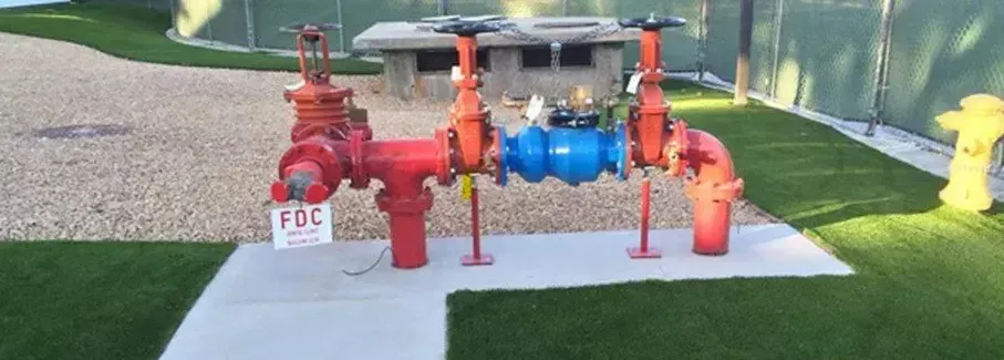 A red fire hydrant is sitting in the grass next to a yellow fire hydrant.