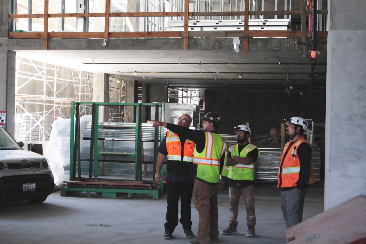 A group of construction workers are standing in a building under construction.