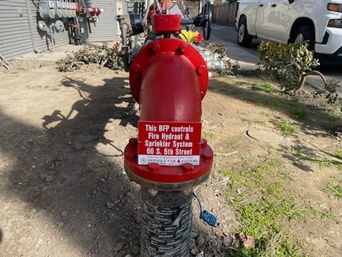 A red fire hydrant with a sticker on it that says `` this fire hydrant is a sprinkler system ''.