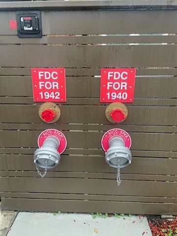 Two fire hydrants are attached to a wooden wall with signs that say fdc for 1942 and fdc for 1940.