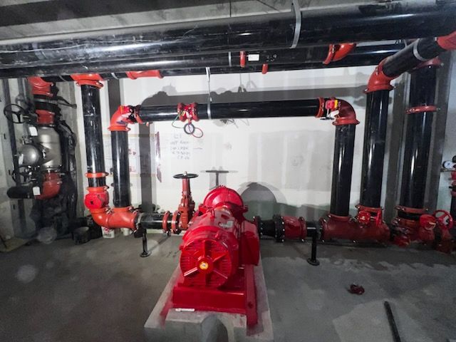 A room with a lot of pipes and a red pump
