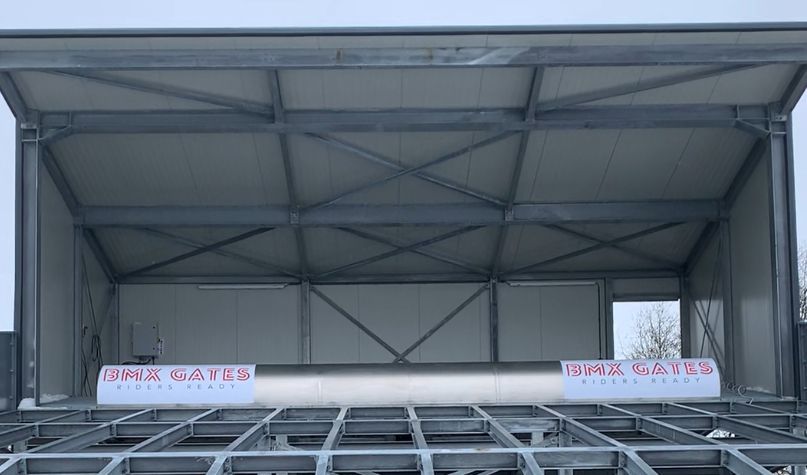 Metalen podiumconstructie met grijs frame en witte panelen. Op het spandoek staat 
