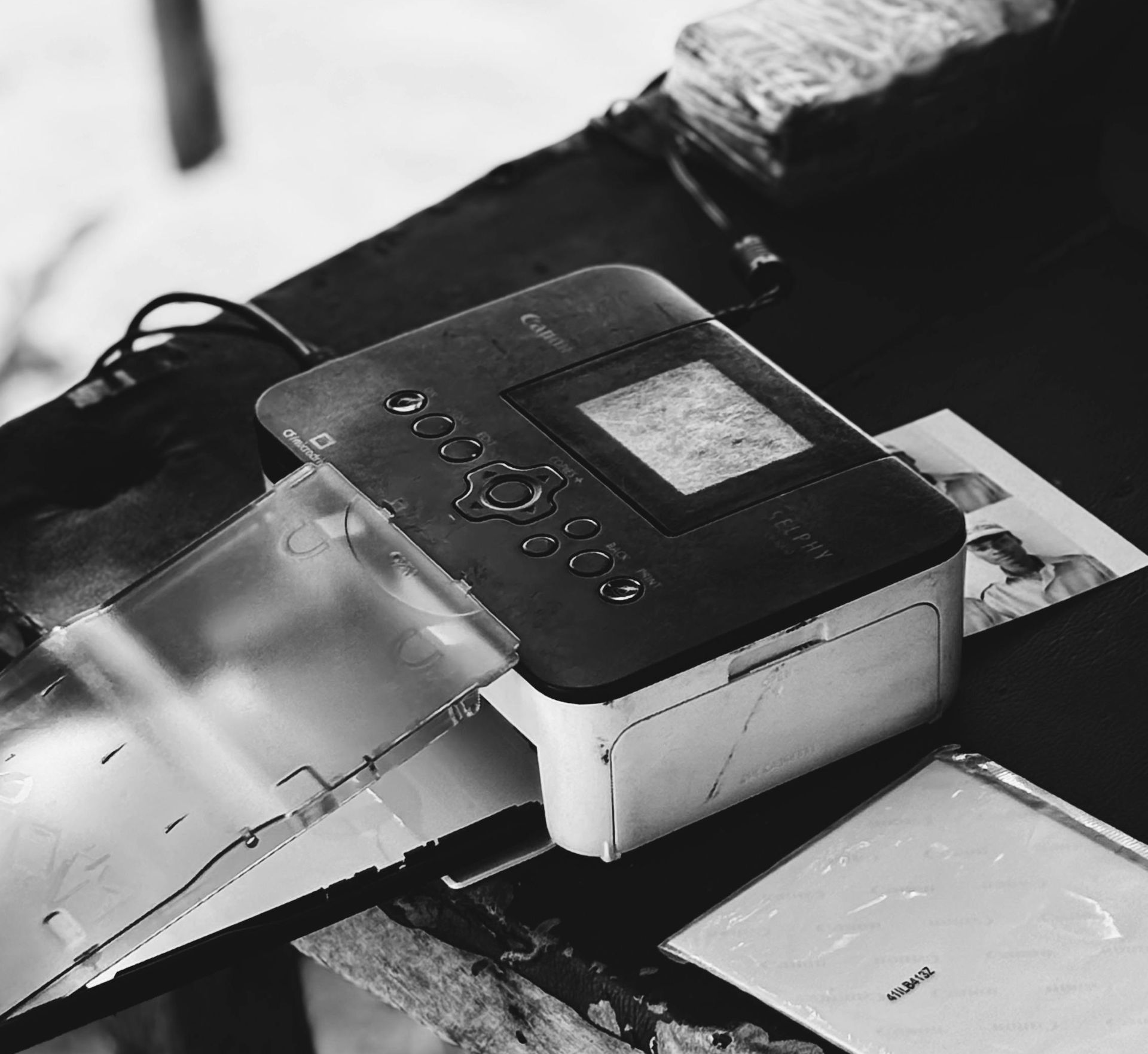 Black and white photo printer on a dark wooden surface with a printed photo nearby.