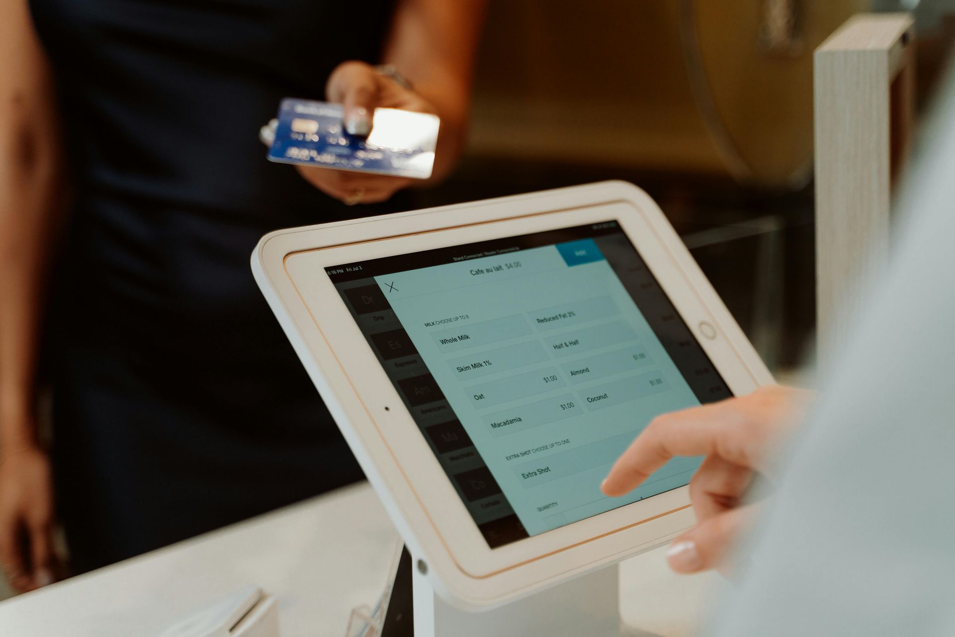 Person paying with credit card at a touchscreen point-of-sale system.
