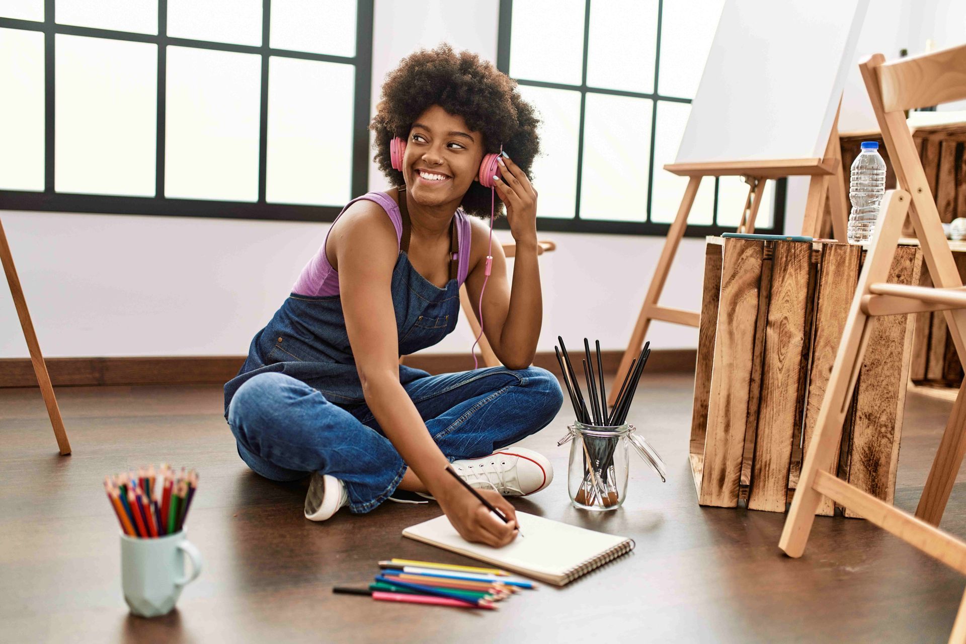 a woman sits on the floor listening to music while doing painting
