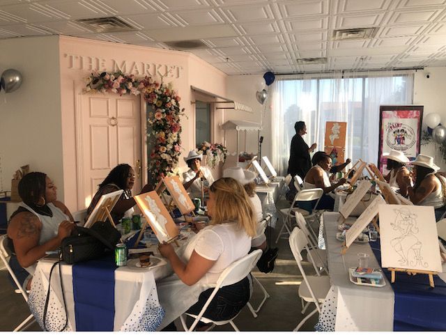 a group of people are sitting around a table painting