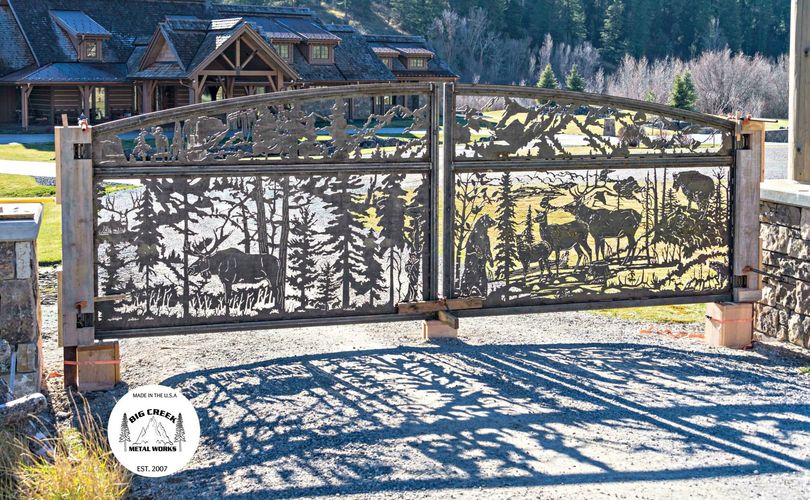 A large metal gate with a picture of trees on it is in front of a house.