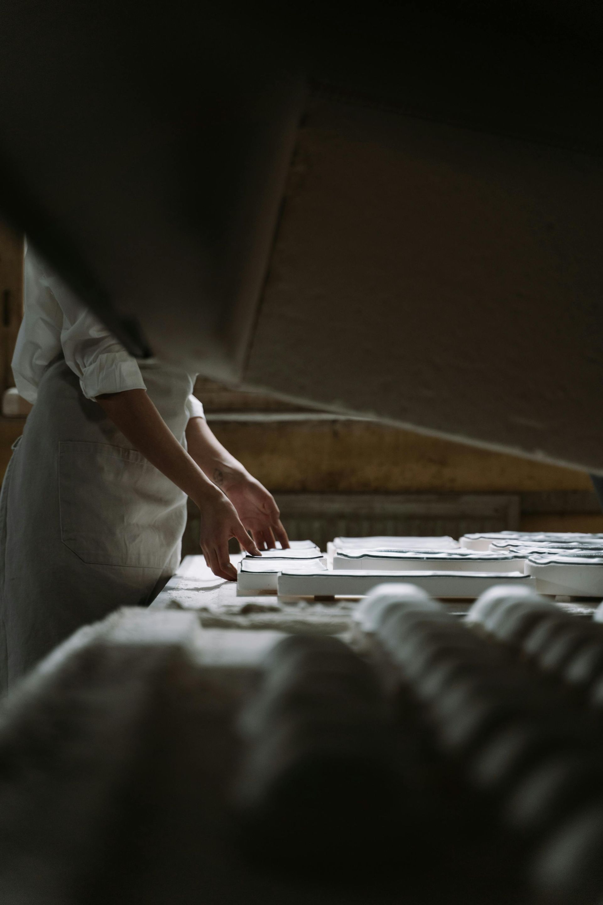 A person is rolling dough on a table in a bakery.