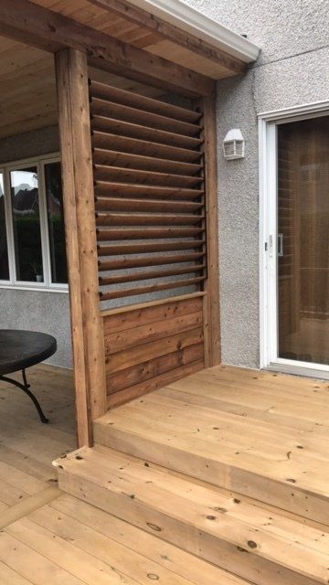 A wooden deck with stairs and a table in front of a house.