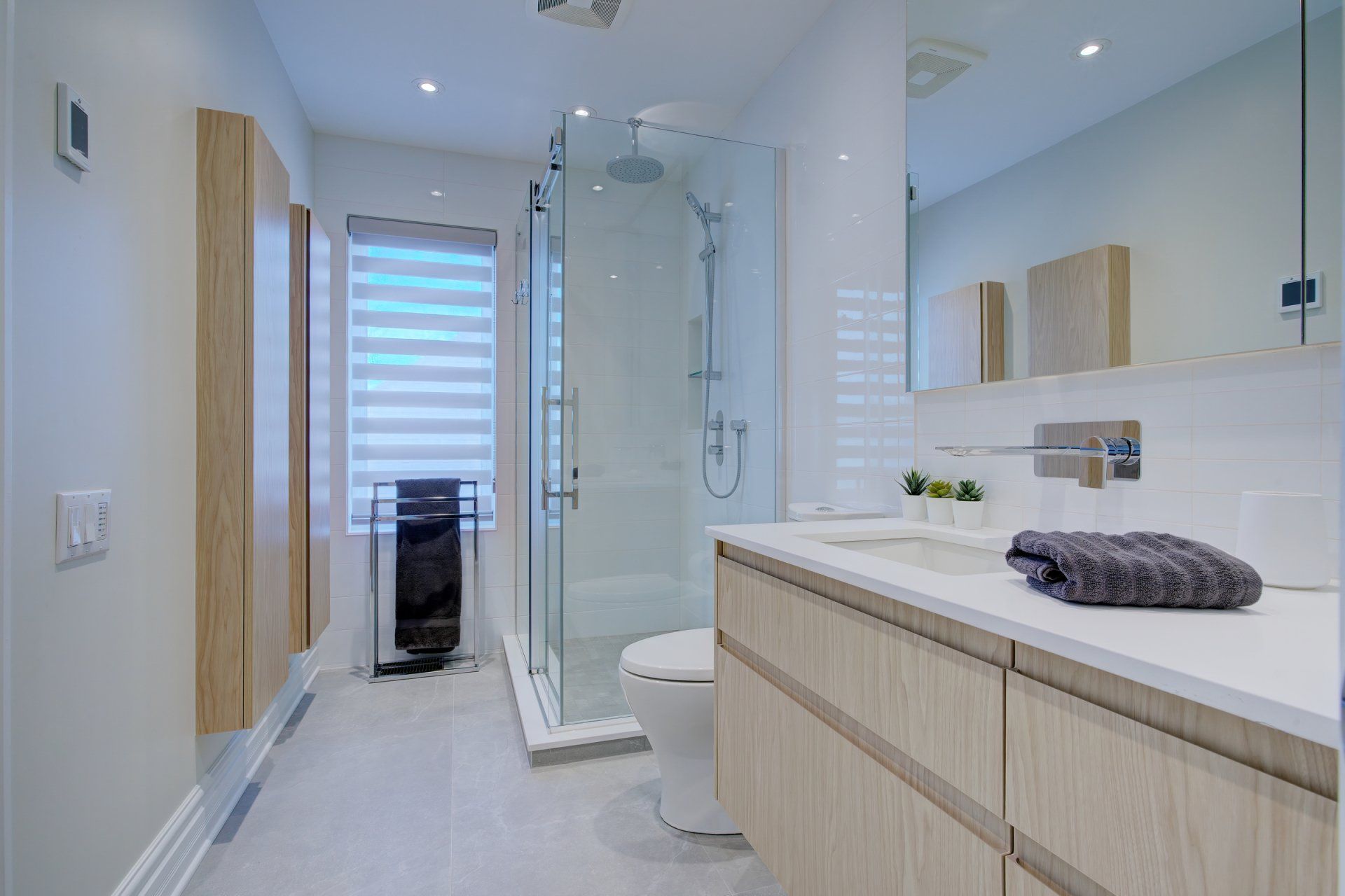 A bathroom with a toilet , sink , mirror and walk in shower.