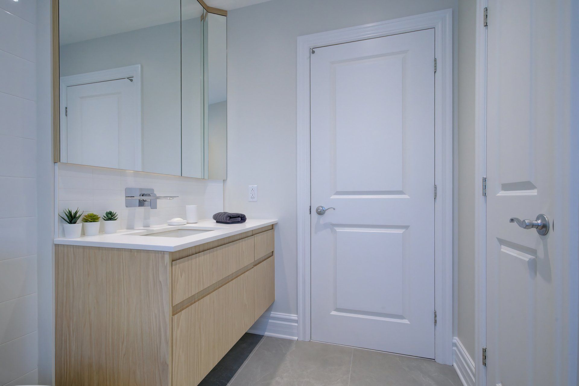A bathroom with a sink , mirror and door.