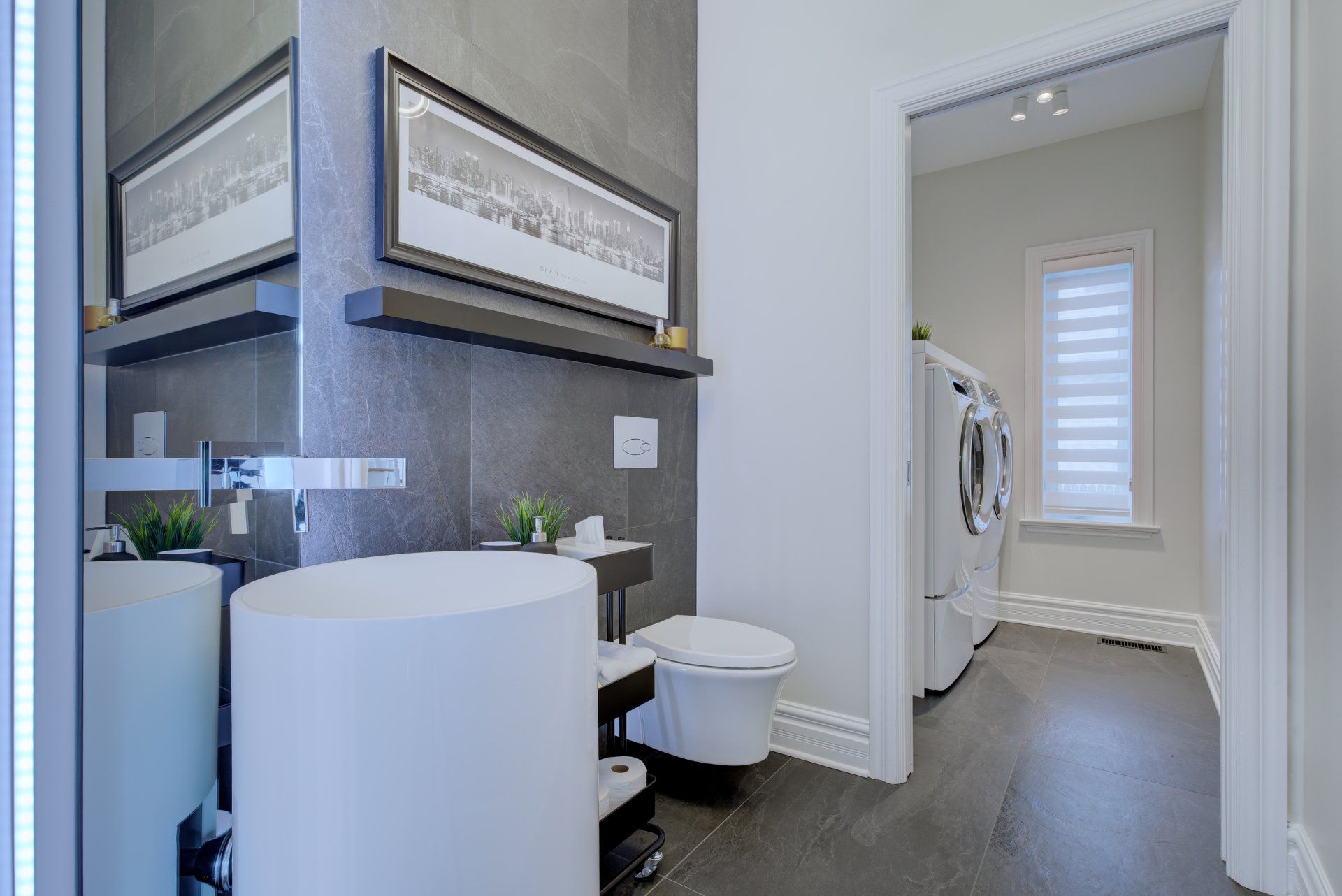 A bathroom with a sink , toilet , mirror and washer and dryer.