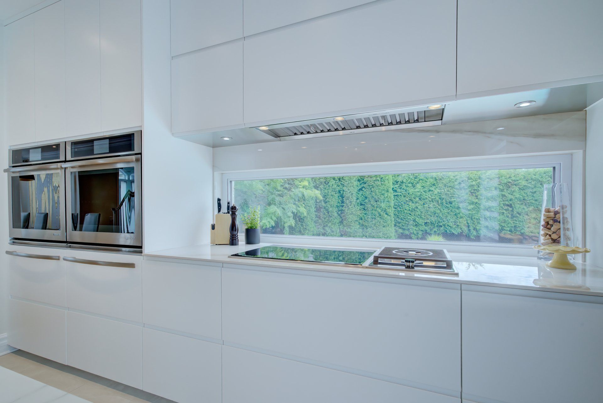 A kitchen with white cabinets and stainless steel appliances and a large window.