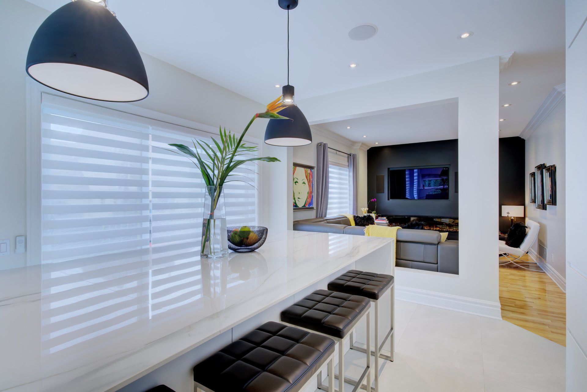 A kitchen with a long counter and stools and a tv on the wall.
