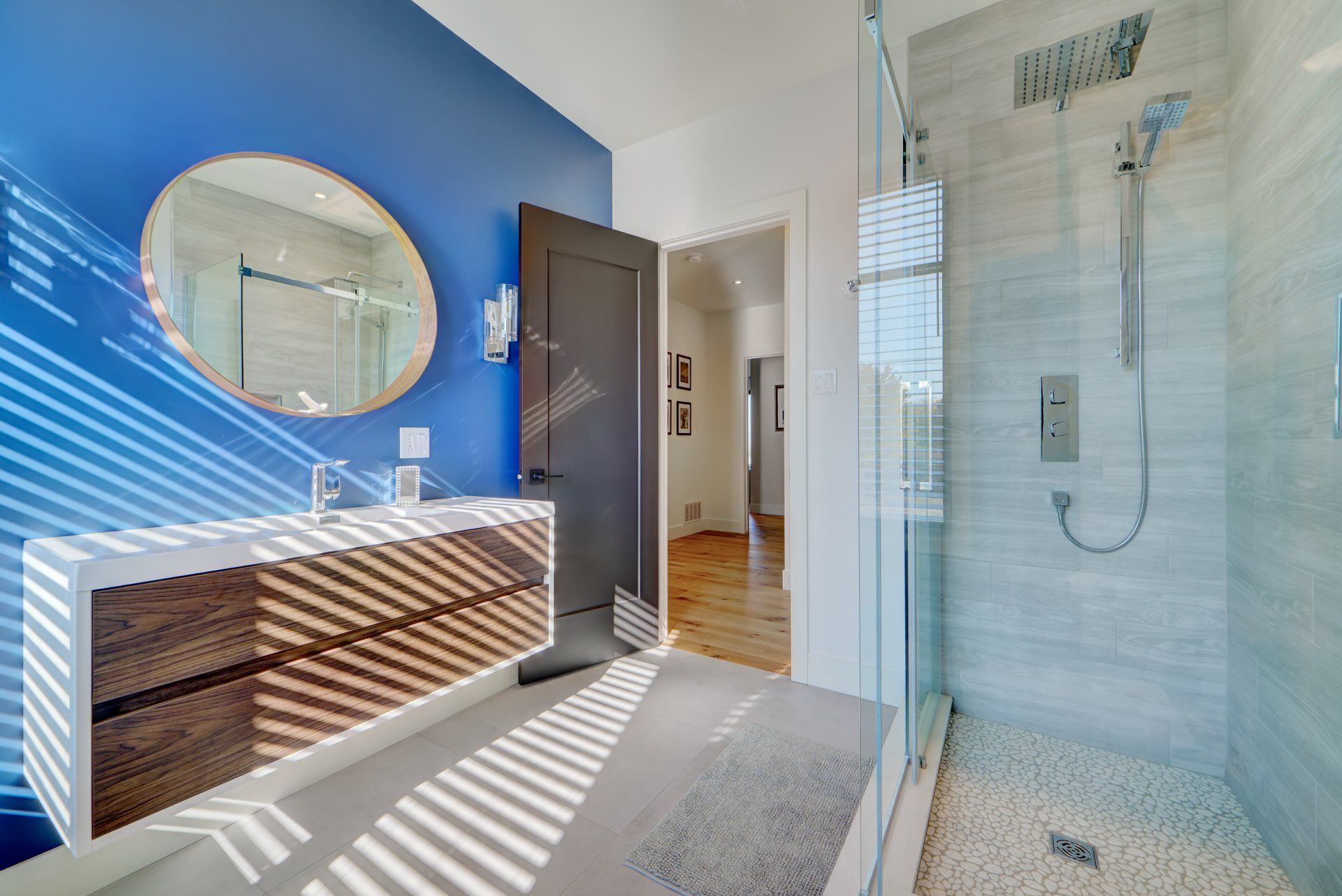 A bathroom with a walk in shower , sink and mirror.