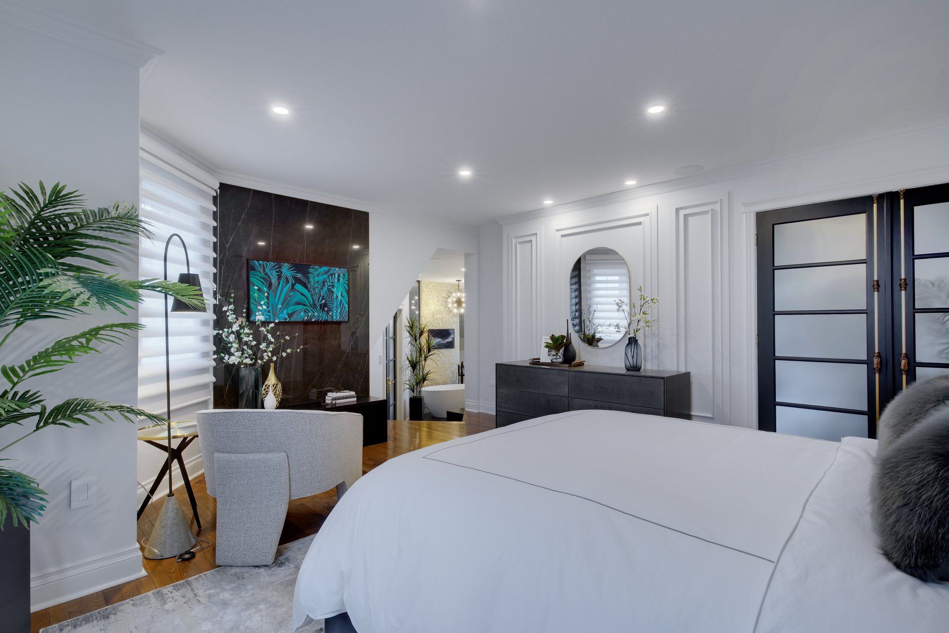 A bedroom with a large bed , dresser , mirror and television.