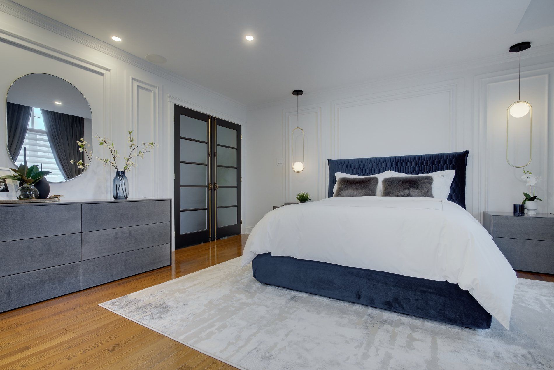 A bedroom with a bed , dresser , nightstand and mirror.