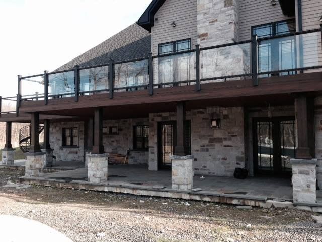 home with large wooden terrace with glass and aluminum railings