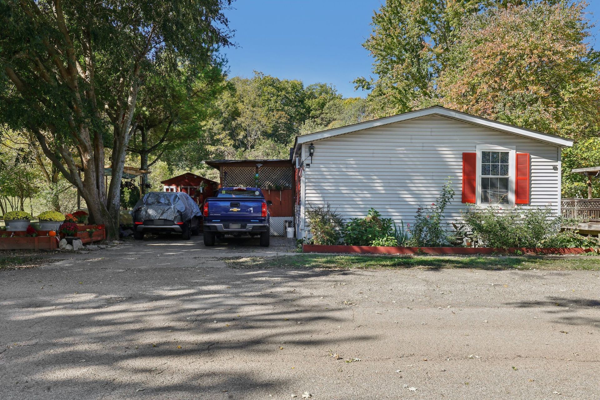 Small white house with red shutters and two vehicles parked in front.