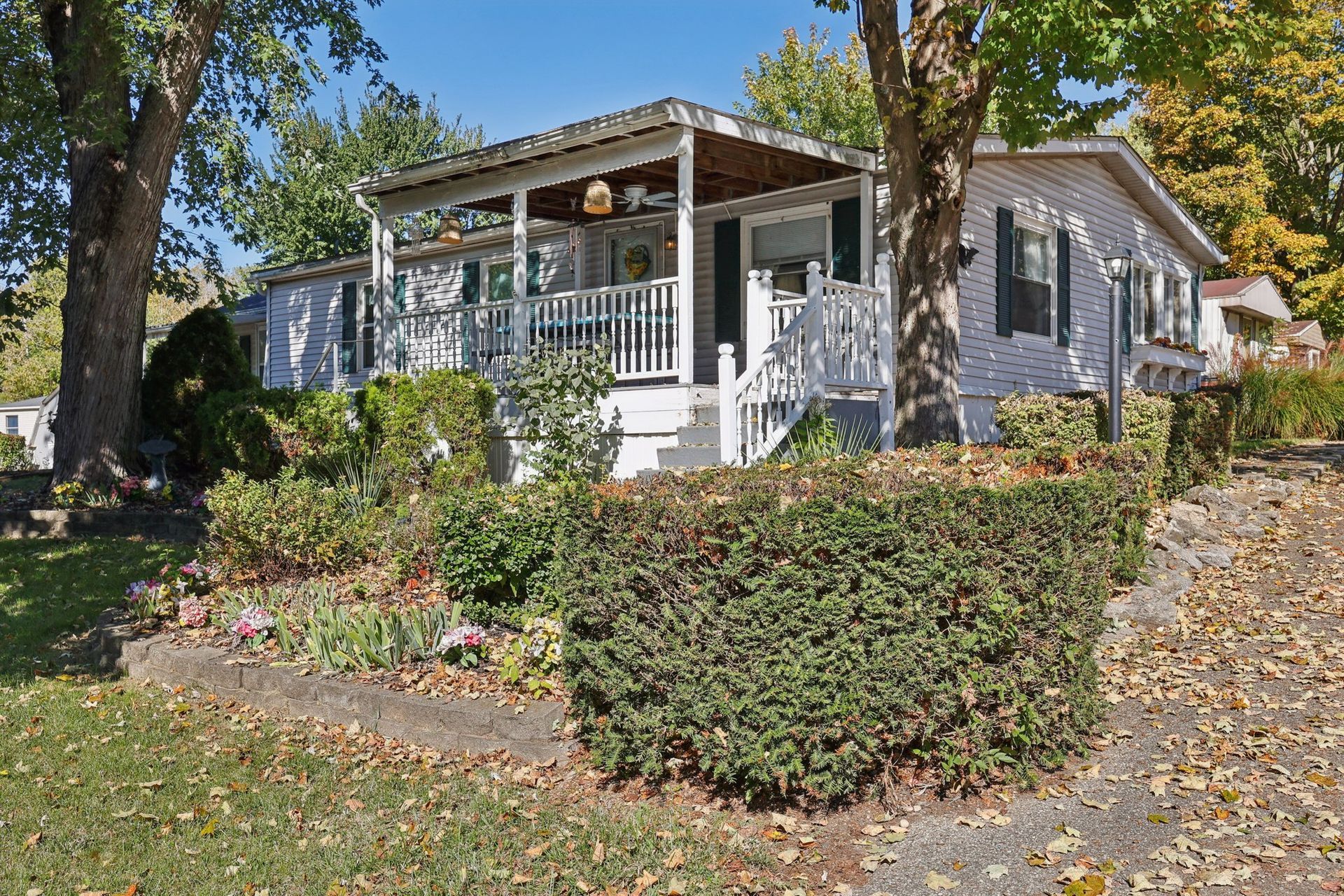 White house with porch and landscaping on a sunny day.