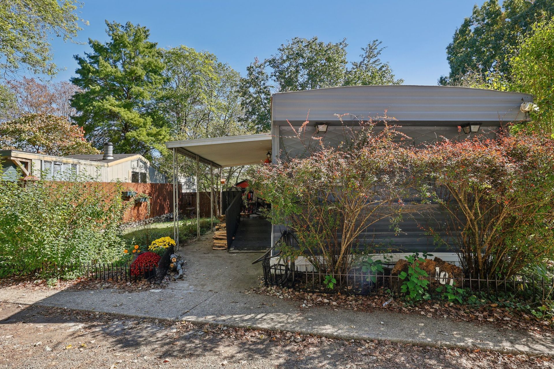 Mobile home with awning, surrounded by landscaping, path leading to the entrance.