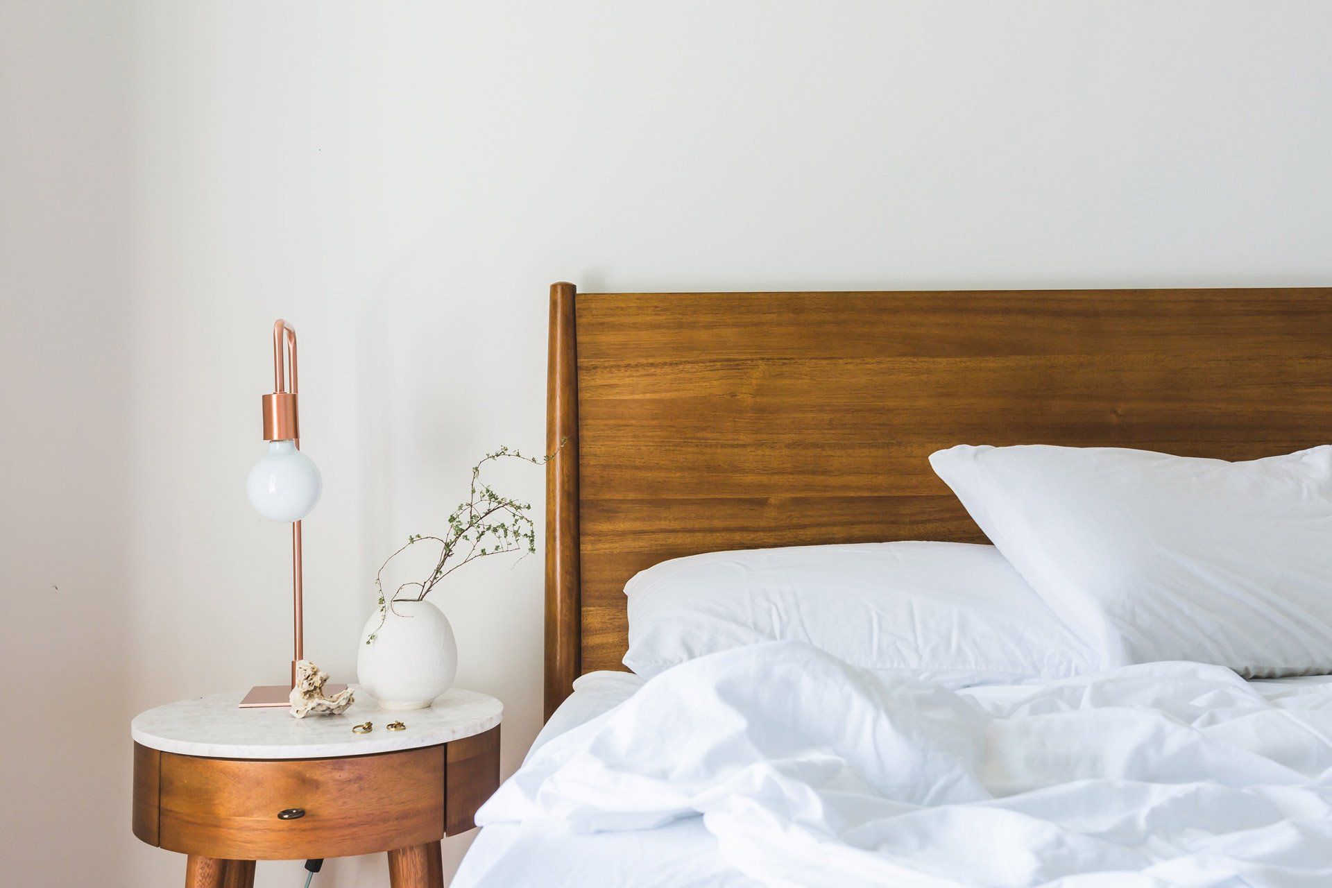 Seng i tre med hvitt sengetøy og nattbord gir hotellfølelsen på soverommet
