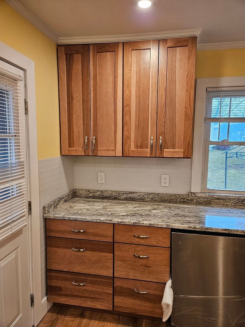 A kitchen with a granite counter top and white cabinets.