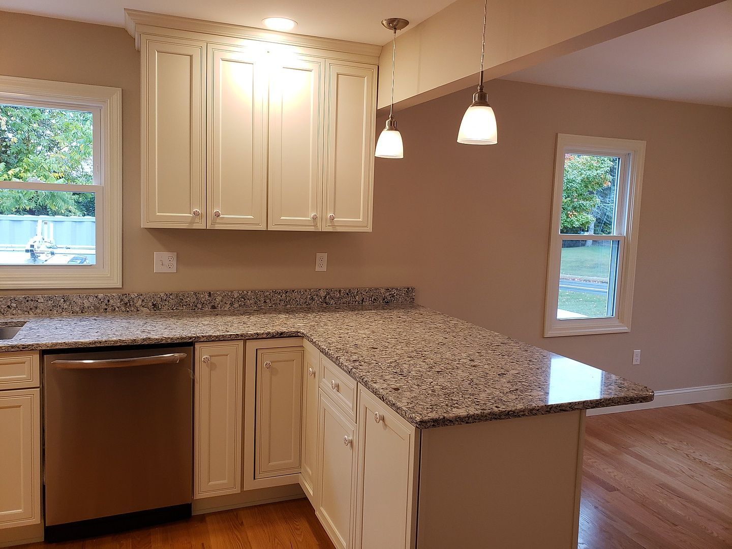 A kitchen with granite counter tops , white cabinets and a stainless steel dishwasher.