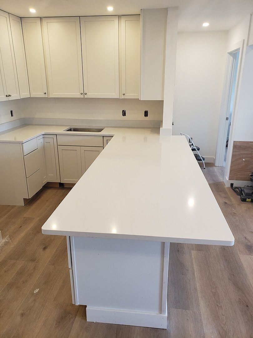 A kitchen with white cabinets and a long white counter top.