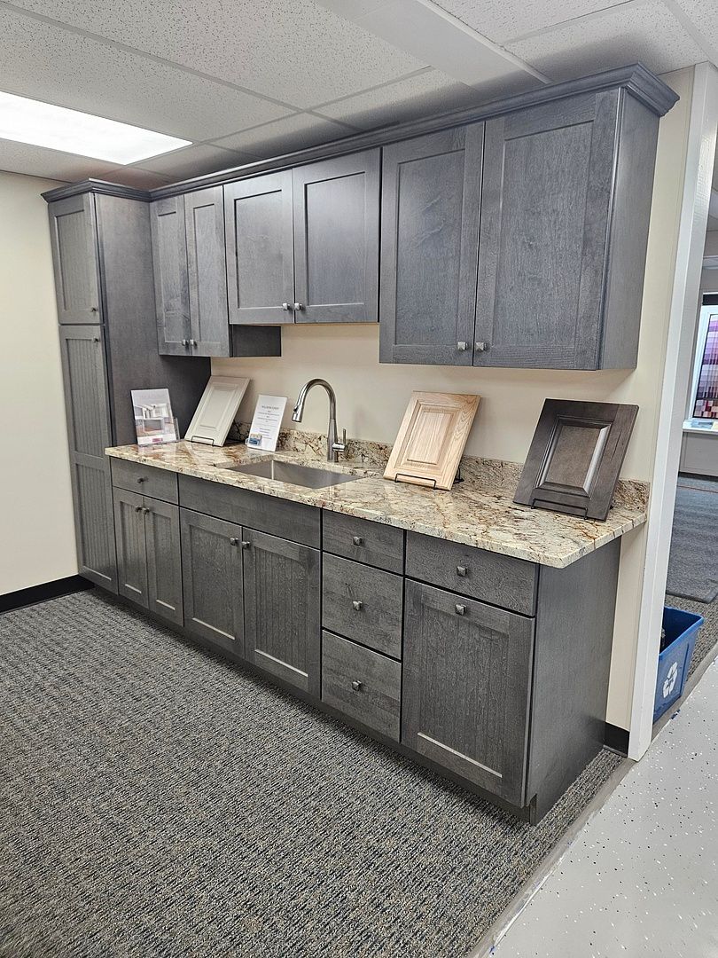 A kitchen with gray cabinets and granite counter tops.