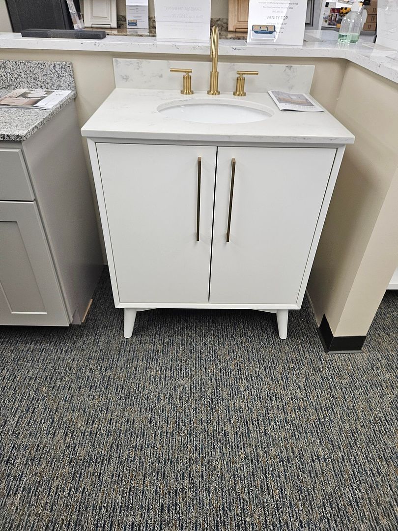 A white vanity with a sink and faucet in a bathroom.
