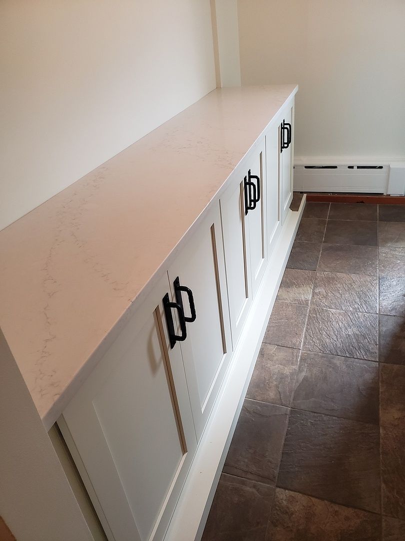 A kitchen with white cabinets and a long white counter top.