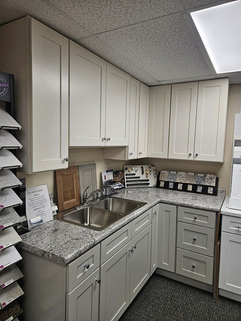 A kitchen with white cabinets , granite counter tops , and a sink.