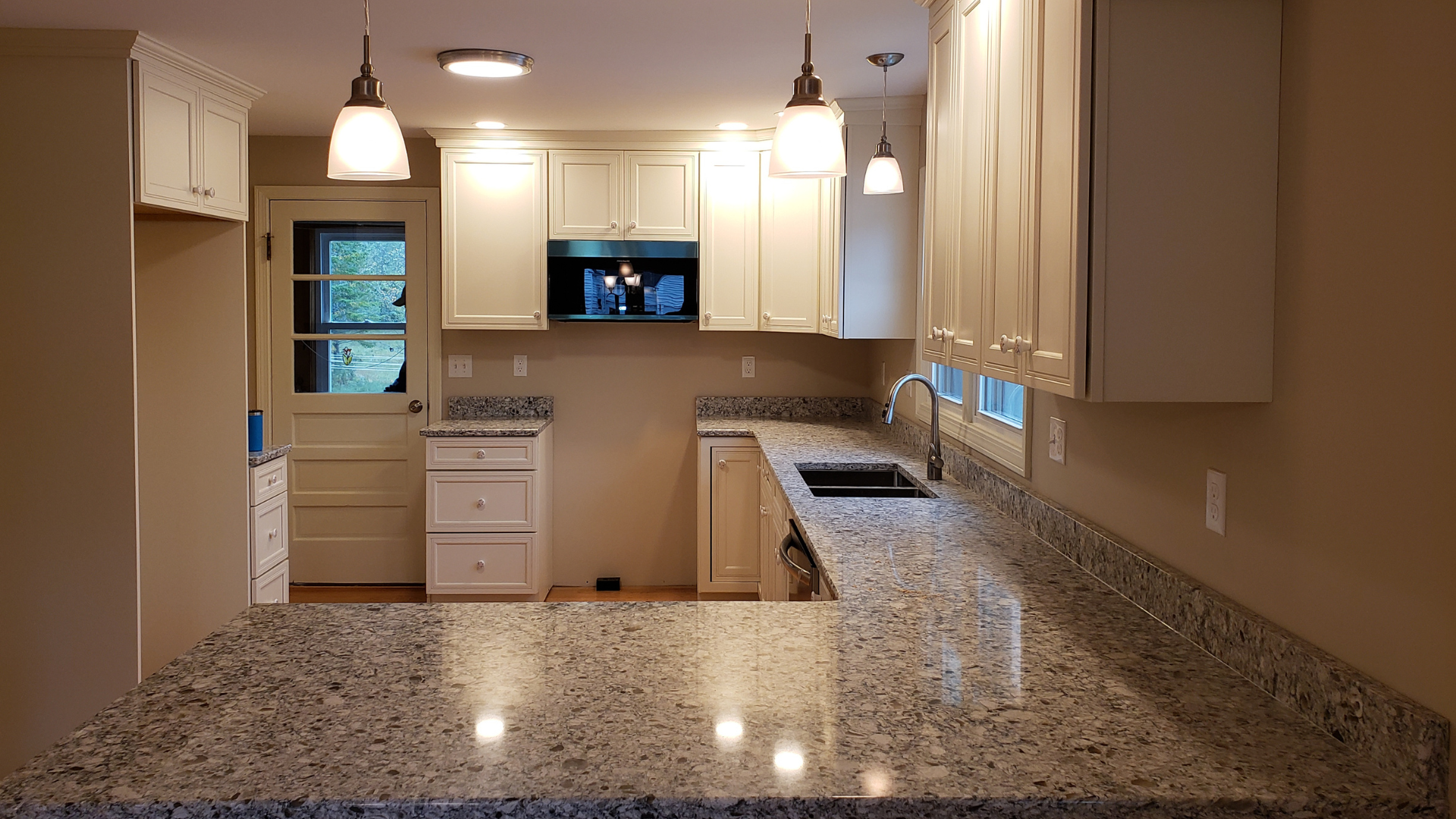 A kitchen with granite counter tops and white cabinets