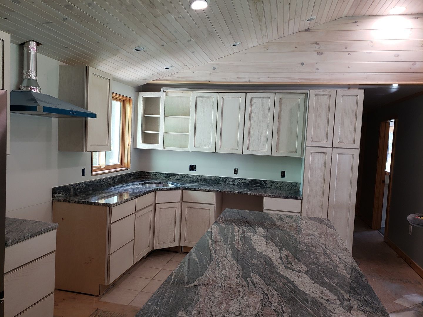 A kitchen with gray cabinets and white counter tops.