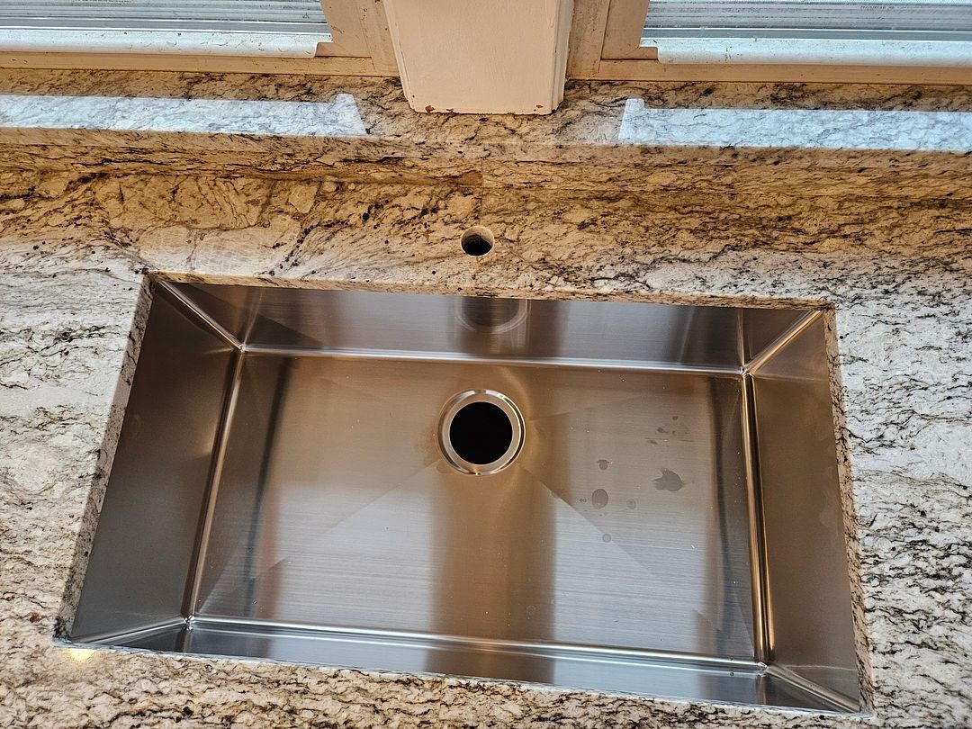 A stainless steel kitchen sink is sitting on top of a granite counter.