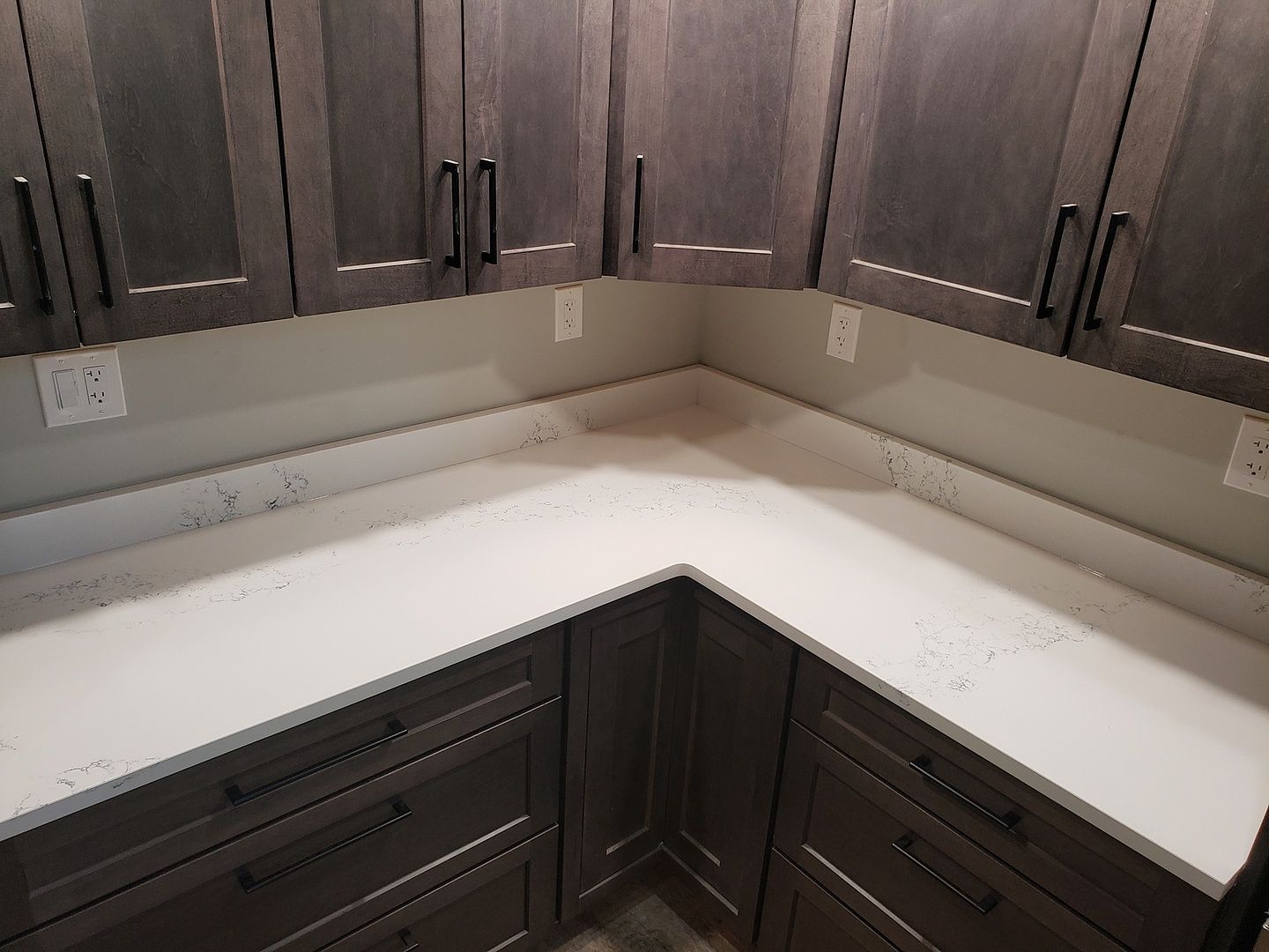 A kitchen with gray cabinets and a stainless steel refrigerator
