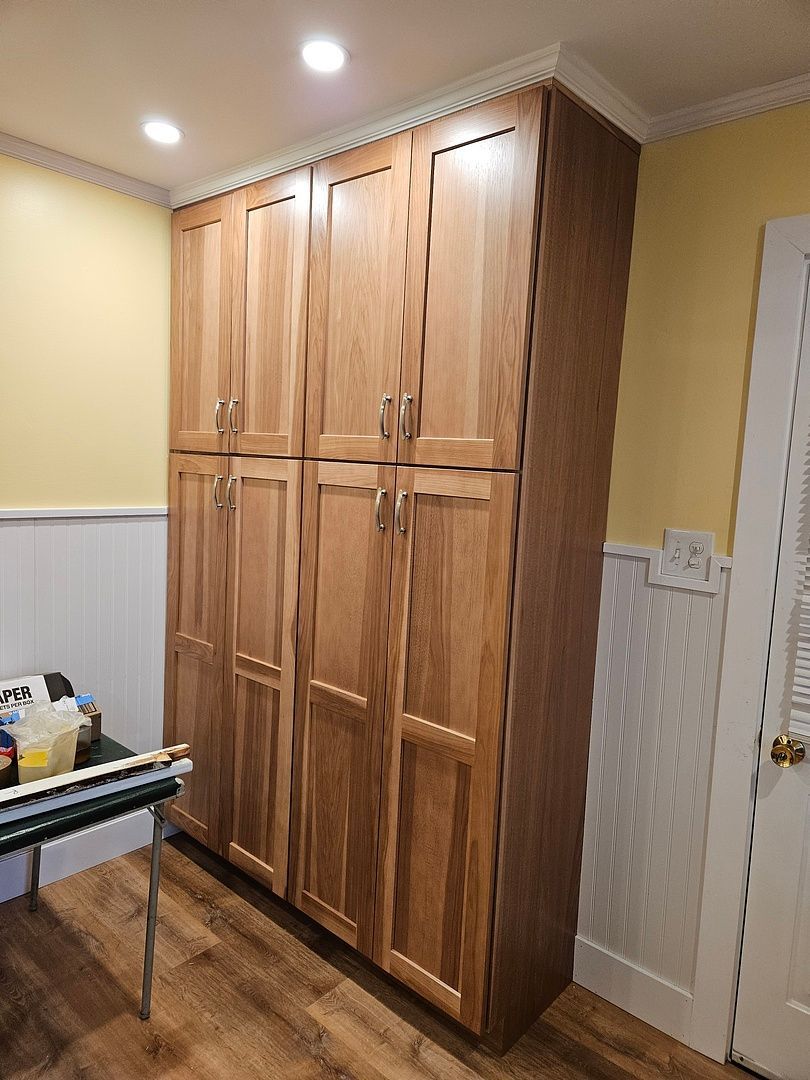A room with a lot of wooden cabinets and a table.