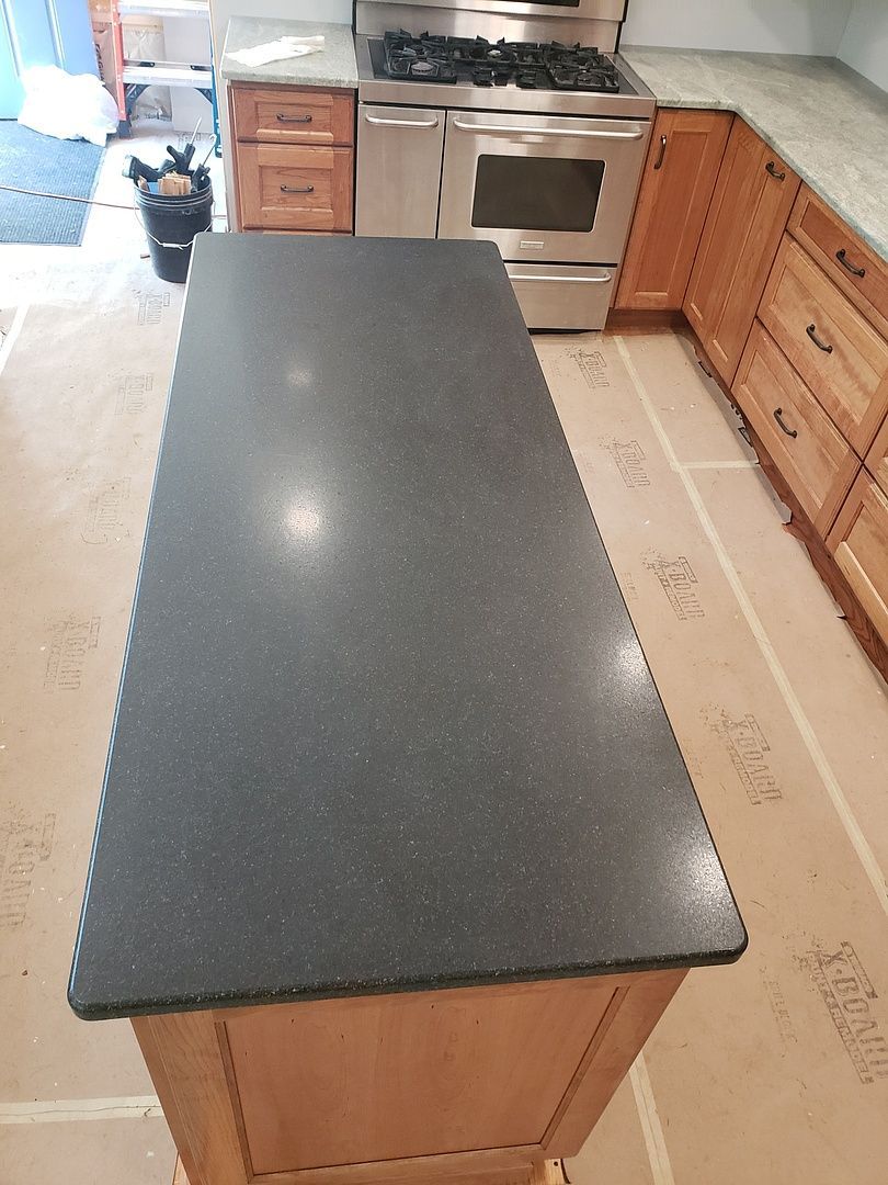 A kitchen with a large black counter top and a stove.