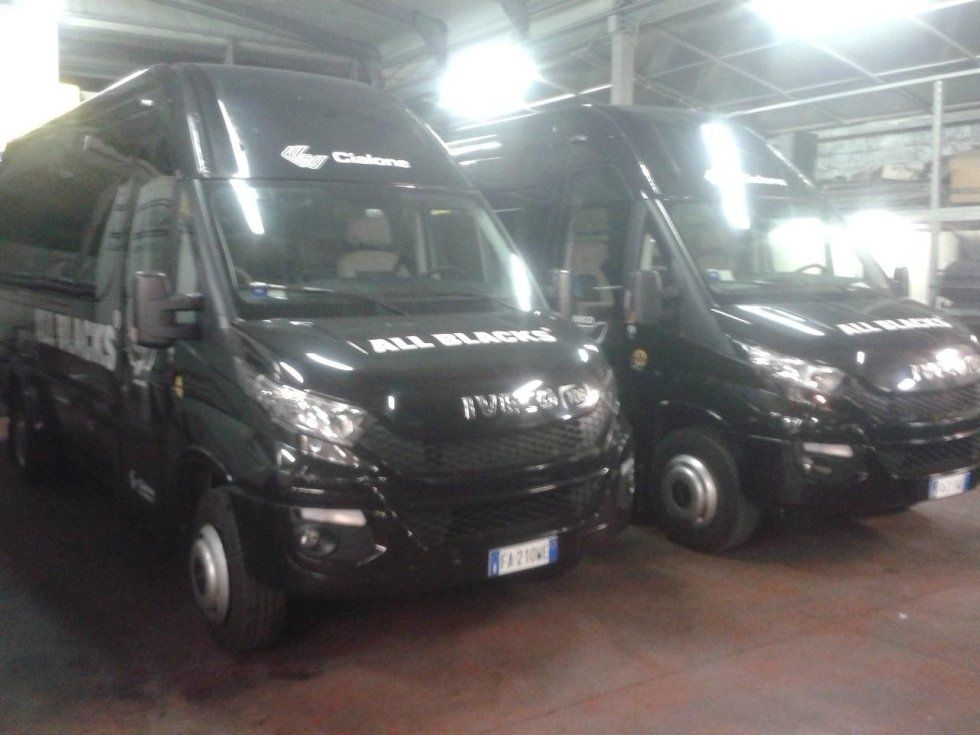 Due furgoni neri parcheggiati in un garage. Sulla fiancata di uno di essi è stampata la scritta