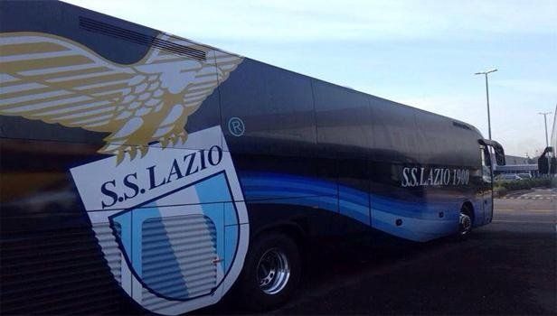 Pullman della SS Lazio con grande stemma del club e aquila, parcheggiato all'aperto. Colori nero, blu e bianco.