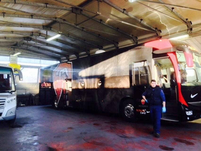 Una persona è in piedi accanto a un autobus nero con decorazioni della Roma