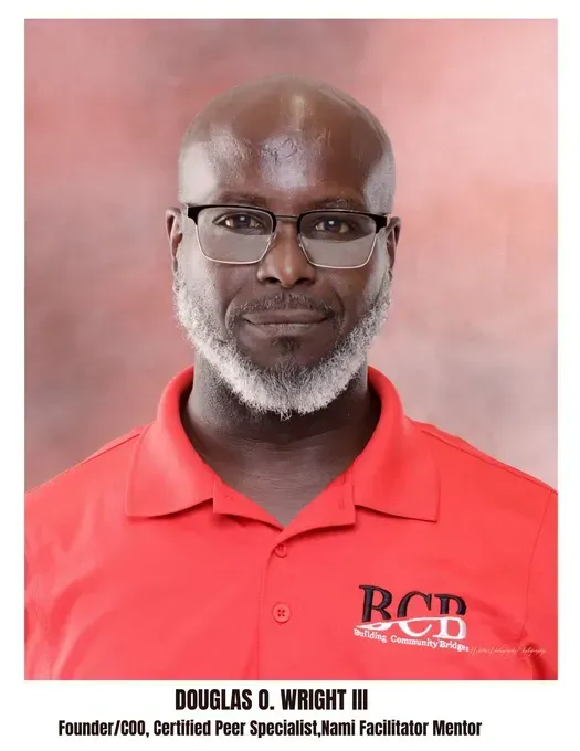 Douglas O. Wright III in a red shirt, wearing glasses, and gray facial hair.