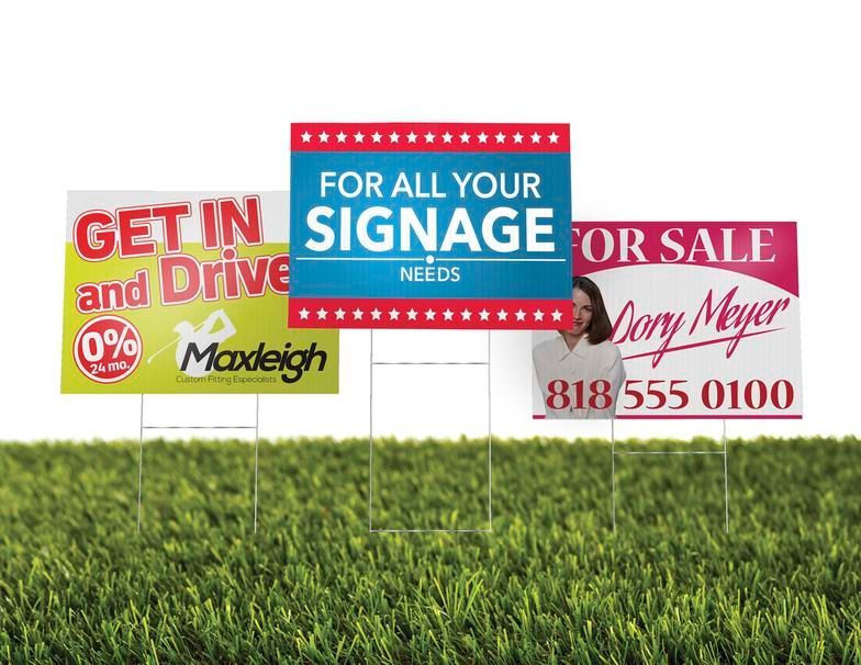 Three signs are sitting on top of a lush green field.