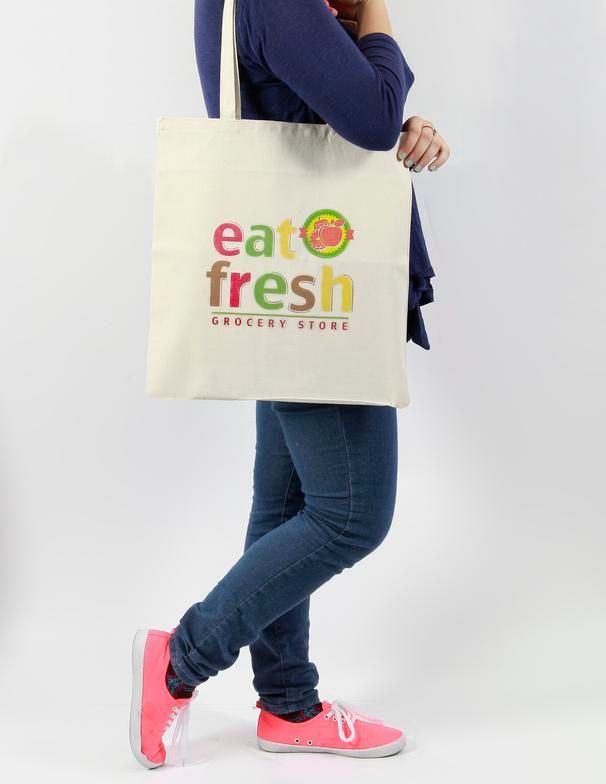 A woman is holding a tote bag that says eat fresh grocery store.