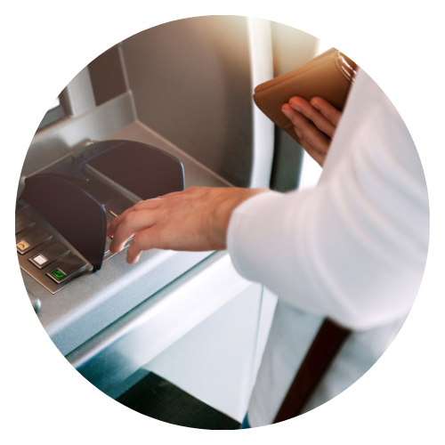 A person is holding a wallet and using an atm machine.